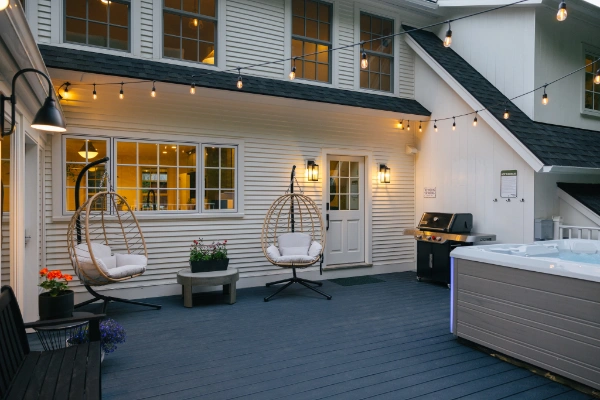 Back deck with grill, seating, and string lights behind the farmhouse